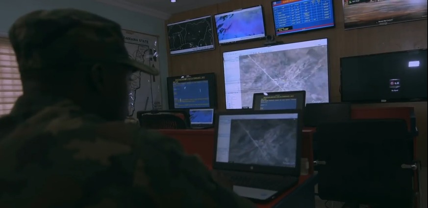 Military officer monitoring satellite imagery and situational displays in an operations command centre
